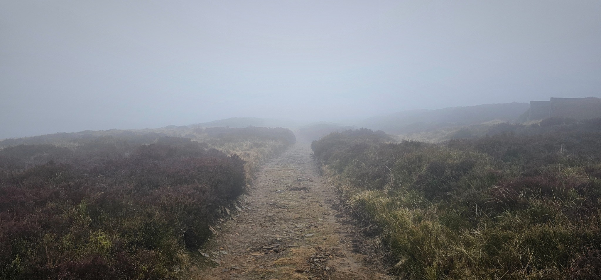 A photo of a foreboding mountain vista with low mist, dark skies and a sense of a challenging path ahead.